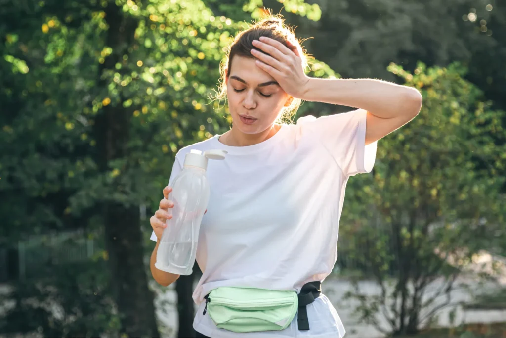 Donna al parco che si tocca la fronte perché ha un capogiro