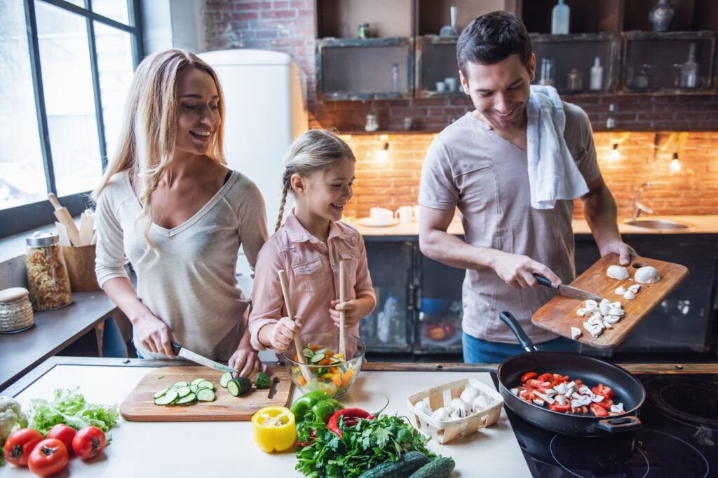 Una giovane famiglia in cui si cucina tutti insieme, composta da mamma, papà e bambina.