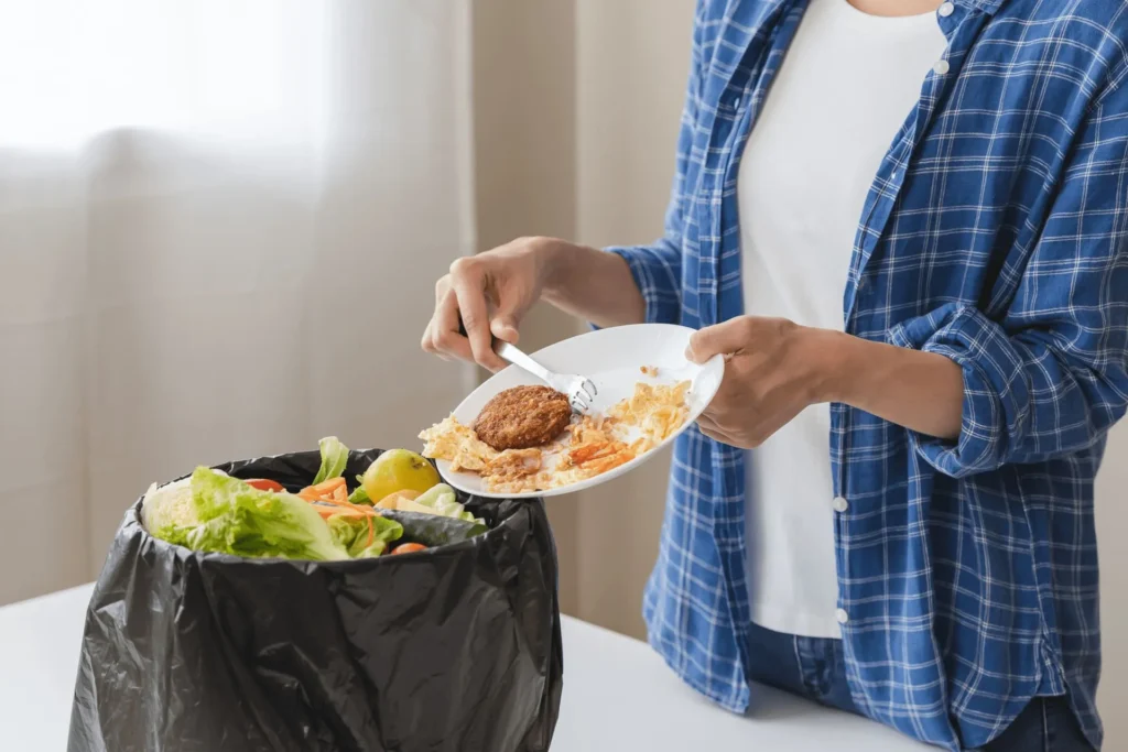 Immagine di persona che getta via cibo avanzato nella spazzatura