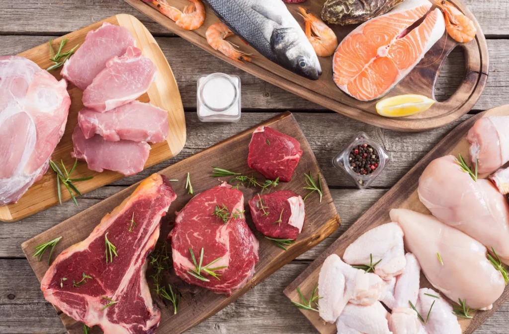 Tavolo imbandito con varie proteine alimentari: carne bianca, carne rossa e pesce